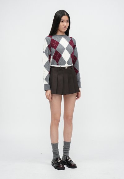 Svetri s argyle vzorom v sivej, bielej a burgundskej farbe. Hnedá plisovaná sukňa so strieborným opaskom. Sivé kolenné ponožky a čierne mokasíny.