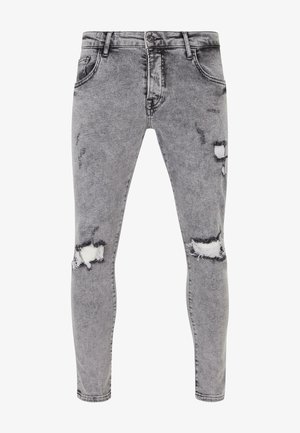 Sivé denimové džínsy so slim fit strihom, s opotrebovanými miestami a roztrhnutiami na kolenách. Päť vreciek s klasickým zapínaním na gombík.