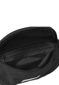 Indvendig i den sorte nylon taske er der en lynlåslomme. Glat tekstur, rektangulær form og åbent design for nem adgang til hovedområdet.