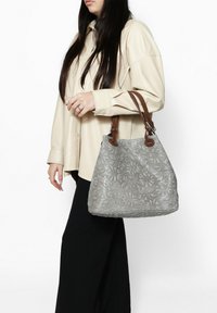 Borsa grigia a rilievo con motivo floreale, in materiale di pelle, e manici marroni. La borsa ha una forma arrotondata e una superficie texturizzata.