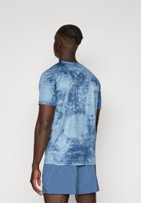 Blauwe graphic T-shirt met korte mouwen, voorzien van een gestructureerd patroon, ronde halslijn en een ontspannen pasvorm. Het materiaal lijkt lichtgewicht en ademend te zijn.