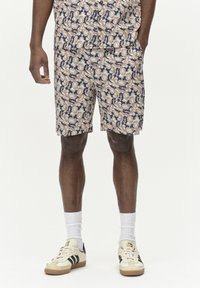Blumenmuster-Shorts in Creme-, Marine- und Rosatönen, mit lockerer Passform, aus leichtem Stoff. Kombiniert mit lässigen Sneakers.