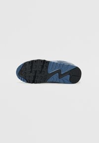 Tălpicul sneaker-ului Nike, de culoare albastră și neagră, cu un design din cauciuc texturat, având un model în zigzag și protuberanțe ridicate pentru aderență.