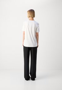 Vit bomull t-shirt med kort ärm, rund halsringning, tillsammans med svarta vida byxor. Enkel, avslappnad passform utan synliga mönster.