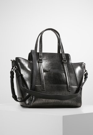 Sac à main en cuir noir brillant avec doubles poignées, poche zippée à l'avant et bandoulière ajustable sur une surface blanche.