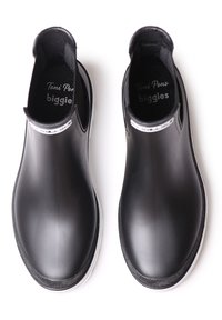 Un par de botas de goma negras de tipo slip-on con suelas blancas visto desde arriba sobre un fondo blanco.