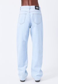 Lyseblå, oversized denim-jeans med høj talje, fem lommer og stikkedetaljer. Bagsiden har et mærketag i livet.