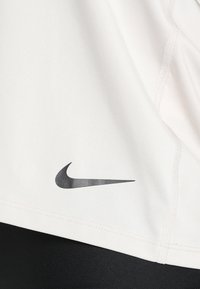 Tissu blanc avec coutures visibles et logo Nike swoosh noir sur fond de tissu noir.