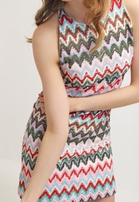 Robe à motif zigzag multicolore en rose, vert, rouge et bleu ; design ajusté avec un col haut et sans manches.