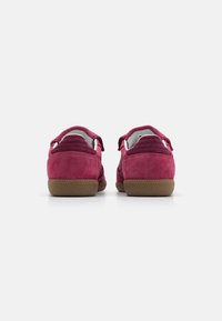 Chaussures en daim violet à profil bas avec une semelle en caoutchouc texturée. Présente des accents cousus et un doublage doux. Vue arrière affichée.