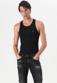 Black cotton tank top with a round neckline and seamless edges, paired with dark gray jeans featuring subtle fading and classic five-pocket design.