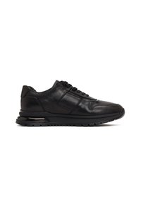 Zapatilla negra de cuero con talón texturizado, cierre de cordones, suela acolchada y suela de goma estriada, mostrada en perfil lateral sobre fondo blanco.