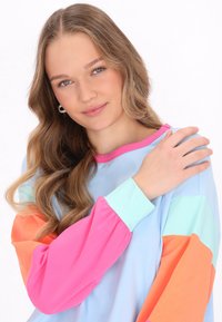 Langärmliges Hemd in Blau, Pink, Orange und Mintgrün. Weicher, leichter Stoff mit farblich abgesetzten Ärmeln und rundem Ausschnitt.