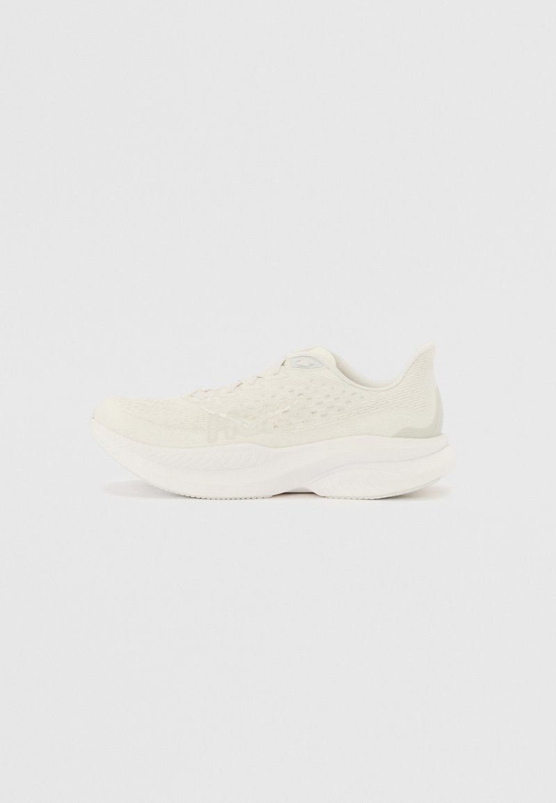 Chaussure de course beige clair avec une tige en maille texturée, une semelle rembourrée et un logo bien en vue. Design élégant avec un bout arrondi et un col rembourré.