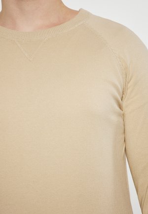 Beige Langarmshirt aus Rippstoff, mit rundem Halsausschnitt und Raglanärmeln mit sichtbaren Nähakzenten.