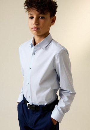 Hellblaues Hemd mit Knopfleiste, glattem Stoff und langen Ärmeln, kombiniert mit dunkler Hose und schwarzem Gürtel.