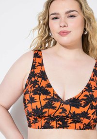 Bralette arancione con motivo palmari neri, scollatura a V profonda, spalline larghe e fascia arricciata per un look aderente. Finitura tessile liscia.