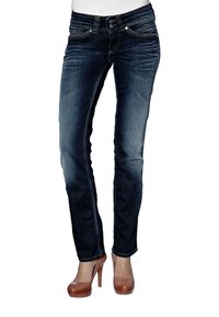 Mörkblå denimjeans med slim fit, med framfickor, dekorativ stickning och knäppning med knapp. I kombination med bruna högklackade skor.