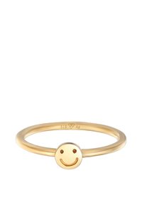 Anillo dorado hecho de plata 925 con una banda lisa y un diseño de cara sonriente en el centro, con grabados en los ojos y la boca.