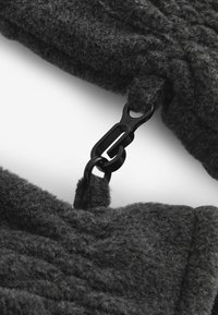 Un tissu texturé gris foncé est relié par un fermoir en métal noir. Le tissu semble doux, avec un motif tissé visible dans le matériau.