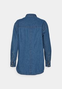 Camicia di denim blu medio, con colletto button-down, maniche lunghe con polsini abbottonati e orlo dritto. La vista posteriore mostra i dettagli delle cuciture.