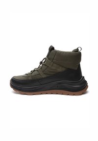 Bottes basses vert olive avec une semelle noire texturée. Elles comportent des bandes élastiques, une languette de tirage et un bout arrondi pour un soutien et un confort accrus.