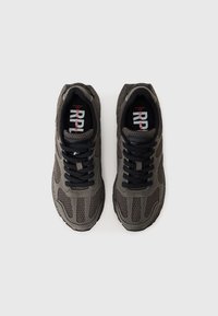 Paire de baskets de sport en mesh gris avec des lacets noirs vues de dessus sur un fond gris clair.