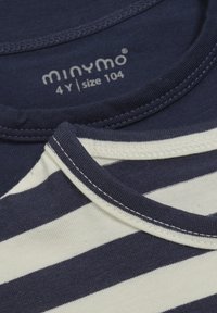 Zwei übereinander gestapelte T-Shirts; eines in einfarbig Marineblau, das andere in Creme mit Marineblau gestreift. Beide haben einen gerippten Halsausschnitt und eine weiche Baumwolltextur.