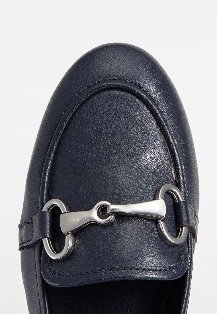 Mocasines de cuero en color navy con punta redondeada, que cuentan con un acento decorativo de hardware plateado y detalles de costura a lo largo de los bordes.