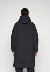 Zwarte lange jas met een capuchon, met een gladde textuur, iets taps toelopende mouwen en een rechte zoom. Eenvoudig ontwerp zonder zichtbare accenten.