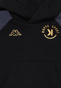 Hoodie noir avec des accents bleu foncé, arborant un logo Kappa Sport en or. Fabriqué en coton doux avec une poche avant et un capuchon à cordon.