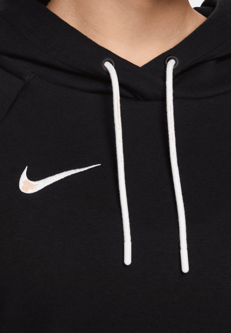 Sweat à capuche noir avec des cordons blancs et un logo Nike Swoosh blanc sur la poitrine gauche, porté par une personne.