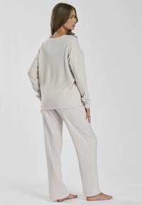 Lichtbeige ribbed loungewear set met een losse top met lange mouwen en wijde broekspijpen, gemaakt van zachte, gestructureerde stof.