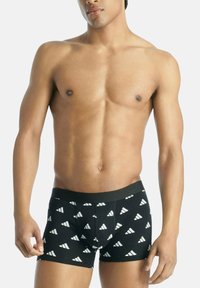 Boxer in nero con un motivo triangolare bianco ripetuto, vita elasticizzata e tessuto morbido, che si adatta perfettamente.