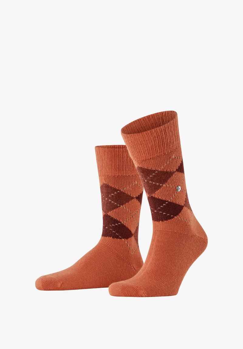 Orange Argyle-Socken mit geripptem Bund, die braune Rauten-Muster und ein kleines Logo-Detail an der Seite aufweisen. Weiche Stricktextur.