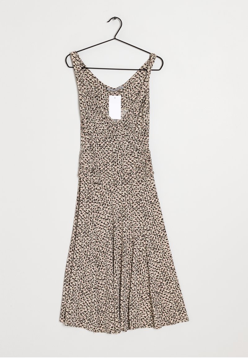 Robe à motifs floraux en beige clair avec des taches foncées, présentant un col en scoop, un corsage ajusté, et un bas évasé. Accrochée à un crochet noir.