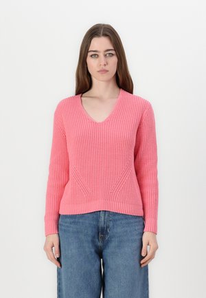 Maglione a maniche lunghe con scollatura a V in maglia rosa brillante. Presenta motivi testurizzati orizzontali e diagonali. Abbinato a jeans blu larghi.