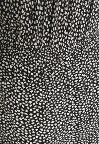 Svart klänning i tyg med ett vitt bladmönster, samlad midja, slät textur och plisserade detaljer för ökad visuell åtnjutning.