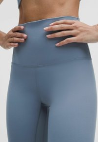 Magas derékszabású, egyszínű, világoskék leggings, rugalmas anyagból, sima tekstúrával és lapos varrásokkal a kényelem érdekében.