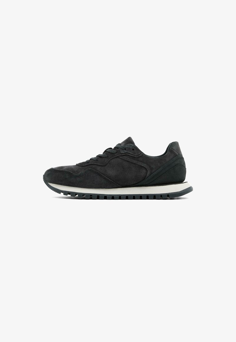 Black suede athletic shoe with a round toe, lace-up closure, and a white midsole. Features textured accents and a ridged rubber outsole.