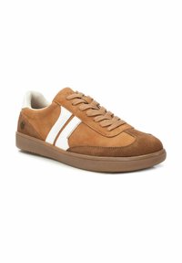 Zapatillas de ante marrón con acentos blancos, punta redonda y suela de goma plana. Cuenta con un cierre de cordones y paneles laterales texturizados.