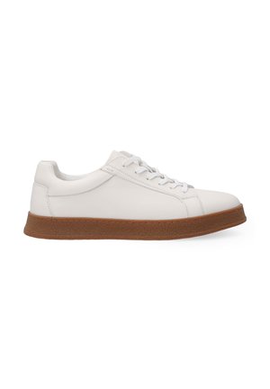 White leather sneaker with a smooth surface, round toe, and brown textured rubber sole. Features white laces and minimal stitching detail.
