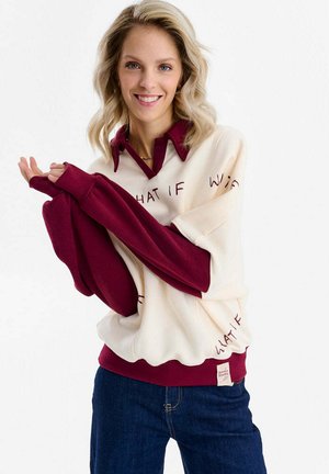 Kremowa i bordowa bluza z długim rękawem, z napisem "WHAT IF" w stylu kursywy, z kołnierzykiem i ściągaczami na rękawach. Idealna do zestawienia z denimem.