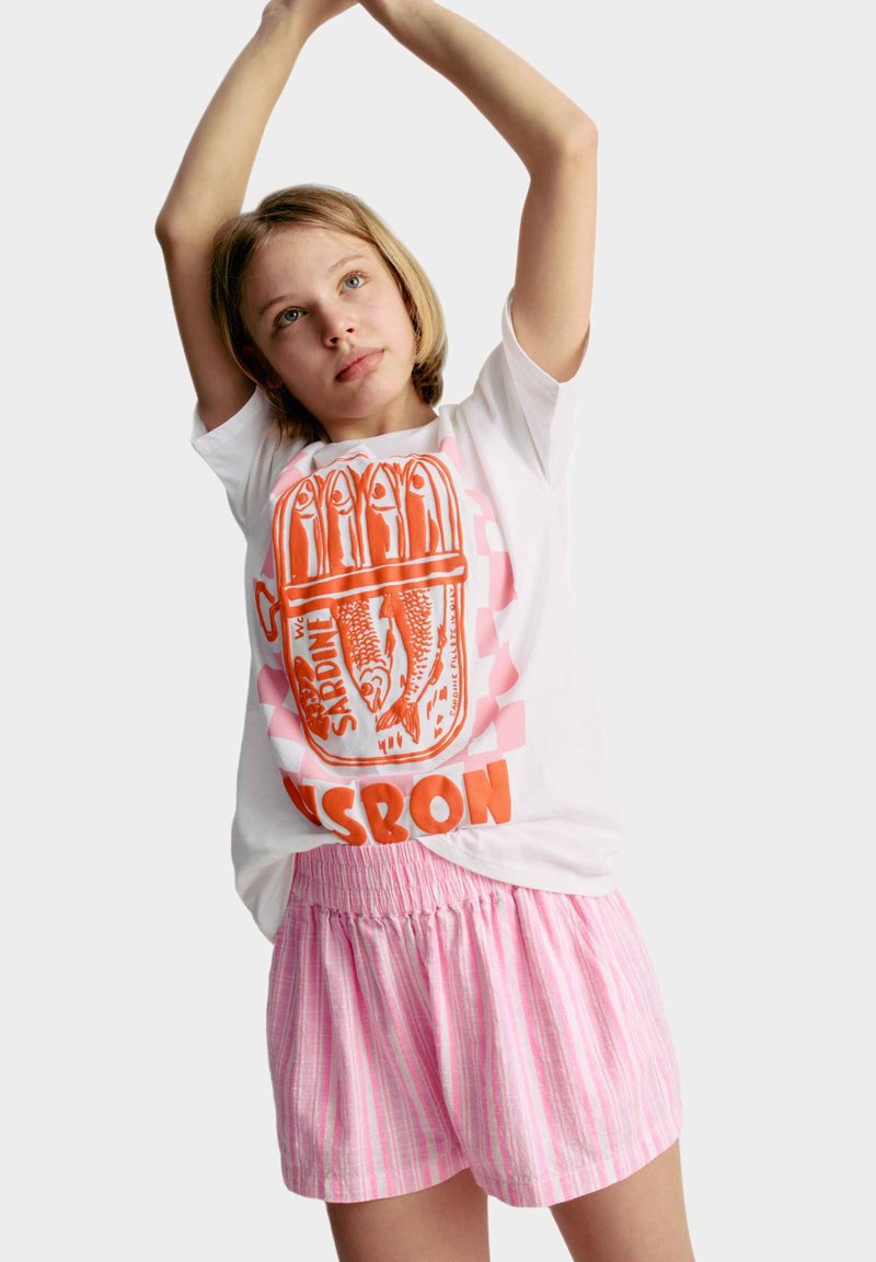 Witte t-shirt met korte mouwen met een oranje sardineblikje grafiek en het woord "Lissabon." Gecombineerd met lichtroze gestreepte shorts met elastische taille.