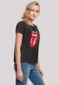 Black cotton t-shirt featuring a prominent red Rolling Stones tongue logo on the front. Short sleeves and a standard fit design.