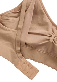 Sujetador beige sin costuras con tirantes ajustables, cierre de gancho y ojal, detalle de tela fruncida en las copas y una banda elástica acanalada en la parte inferior.
