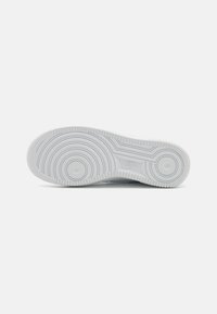 Valge kummist sneakeri välispinna osa ümmarguse mustriga, tekstuursete servadega ja Nike logo, koos sileda ja vastupidava materjaliga.