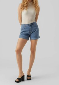 Vaaleansiniset farkkushortsit käännetyillä lahkeensuilla, yhdistettynä kermaiseen ribbineuletankkitoppiin ja korkeisiin mustiin lohkopohjaisiin sandaaleihin.