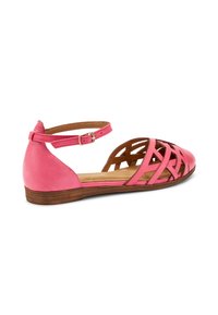 Sandaña plana de cuero rosa con diseño troquelado. Cuenta con una correa en el tobillo, plantilla acolchada y suela de madera marrón. Diseño de punta abierta y parte trasera abierta.
