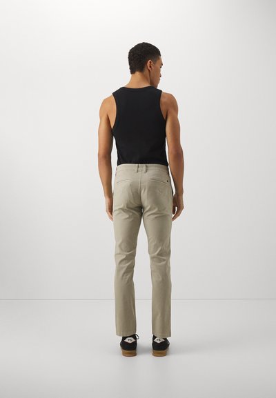 Black sleeveless tank top, light beige trousers, casual style, smooth texture, straight fit, back view, paired with black shoes.